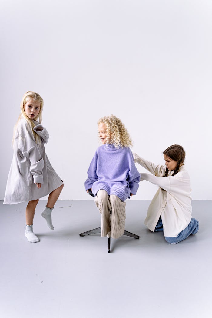 Three young girls posing in a fashion studio, showcasing trendy outfits.